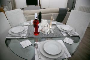a glass table with plates and wine glasses on it at Peace Home in Watford