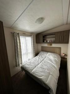 a small bedroom with a bed and a window at Lovely caravan at Martello Beach Holiday Park Sv14 in Jaywick Sands