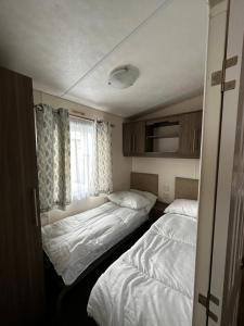 two beds in a small room with a window at Lovely caravan at Martello Beach Holiday Park Sv14 in Jaywick Sands