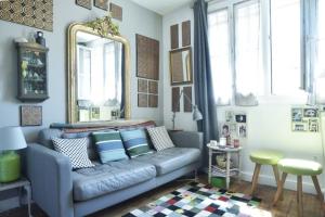 a living room with a blue couch and a mirror at The Atypical - 1 Bedroom in Canal de l'Ourcq in Paris