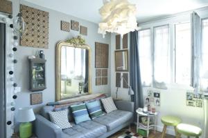 a living room with a couch and a mirror at The Atypical - 1 Bedroom in Canal de l'Ourcq in Paris