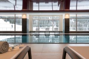 a swimming pool with chairs in a building at Hôtel Alhena in Flaine