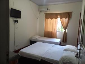 a small room with two beds and a window at Hotel da Gaucha in Cruzeiro do Oeste