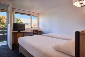 a hotel room with two beds and a television at Kyriad Direct Haguenau in Haguenau