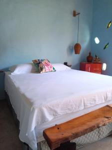 a bedroom with a white bed with a wooden bench at Odoyá Corumbau in Corumbau