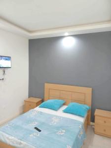 a bedroom with a bed with blue sheets and a television at Norespaço - Le cap sud in Tarrafal