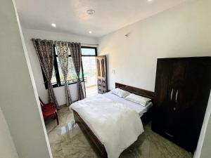 ein Schlafzimmer mit einem Bett und einem großen Fenster in der Unterkunft Tulsi Homestay in Munsyari