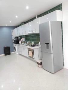 a kitchen with a white refrigerator and green tiles at Norespaço - Le cap sud in Tarrafal