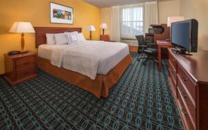 a hotel room with a bed and a flat screen tv at Fairfield Inn & Suites by Marriott Williamsburg in Williamsburg