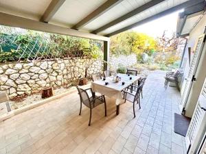 a patio with a table and chairs and a stone wall at Villa Mathilde, deliziosa villetta con spiaggia inclusa in Numana