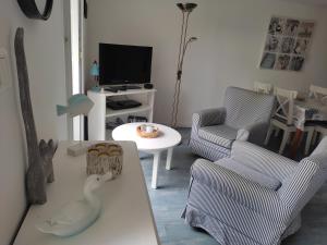 ein Wohnzimmer mit einem Sofa, Stühlen und einem TV in der Unterkunft Petite et grande longères familiale avec jardin - nature & plages in Limerzel