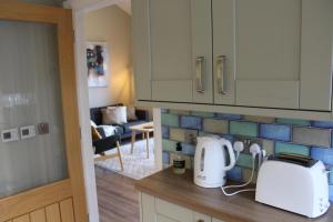 a kitchen with a counter with a toaster and a living room at Betula Chalet – coast & country in the Highlands in Nairn