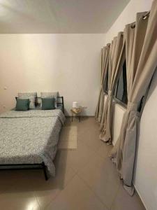 1 Schlafzimmer mit 2 Betten und einem Fenster mit Vorhängen in der Unterkunft Appartement cosy et spacieux in Praia