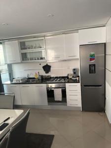 eine Küche mit weißen Schränken und einem Kühlschrank aus Edelstahl in der Unterkunft Appartement cosy et spacieux in Praia