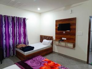 a small room with a bed and a tv at Shri Girraj Residency in Mathura