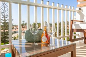 two wine glasses and a bottle on a table on a balcony at Luxury Loft en Maspalomas con Terraza y Piscina in Maspalomas