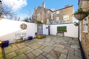 d'une terrasse avec 2 chaises et une table contre un mur blanc. dans l'établissement Stunning Abode in London - Private Garden, à Londres