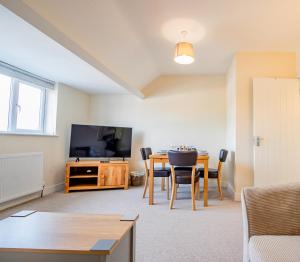 a living room with a dining room table and a television at Newly refurbished apartment in city centre in Hereford