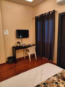 een slaapkamer met een bureau met een monitor en een stoel bij HOTEL KANAL in Kota