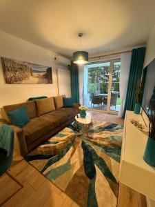 a living room with a couch and a table at Apartament Whiteblue Dream 2 Kołobrzeg z ogródkiem & sauna & fitness & bawialnia dla dzieci in Kołobrzeg