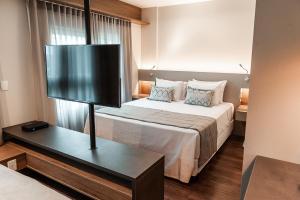 a hotel room with a bed and a flat screen tv at Quality Porto Alegre in Porto Alegre