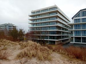 a tall building next to a beach with tall grass at Solaris Apartment Nala in Darłowo