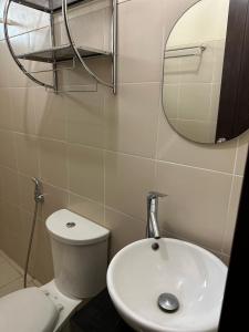 a bathroom with a toilet and a sink and a mirror at 2BR Top Floor spacious unit in Mandaluyong in Manila