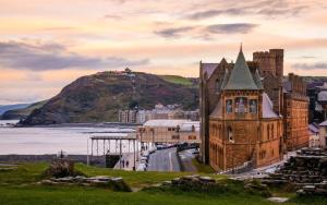 a castle on a hill next to a body of water at The Welsh Black Inn in Aberystwyth