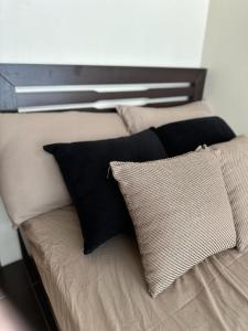 a bed with pillows on it with a window at 2BR Top Floor spacious unit in Mandaluyong in Manila