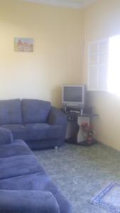 uma sala de estar com um sofá azul e uma televisão em Casa no Centro de Ibitipoca em Lima Duarte
