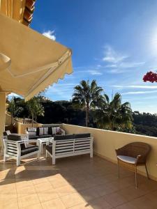 a patio with chairs and tables and an umbrella at R26 Stunning Penthouse Duplex Elviria in Marbella