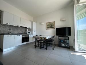 萊萬托的住宿－Silvia House Sea View，厨房配有白色橱柜、桌子和电视。