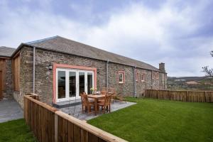 a stone house with a table and chairs in a yard at Byre in Melrose