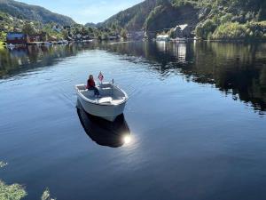 un hombre sentado en un barco en un lago en Sjötun Fjord Cabin, with boat, 