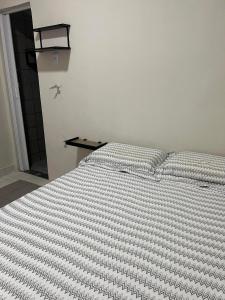 a bedroom with a bed with a striped comforter at Excelentes Quartos com banheiros privativos in Recife