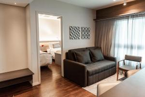 a living room with a couch and a bedroom at Quality Porto Alegre in Porto Alegre