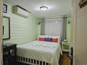 uma cama num quarto com almofadas verdes e vermelhas em W home The Thai-style tranquil and cozy villa em Bangkok