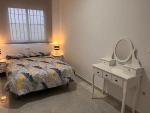 1 dormitorio con cama, tocador y espejo en ALFAROS HOME, en Córdoba