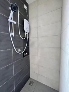 a shower with a shower head in a bathroom at The Deluxe at Horizon Suites KLIA in Kampong Melot