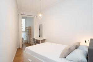 een witte slaapkamer met een bed en een bureau bij Bright and cozy flat in the heart of the city in Barcelona