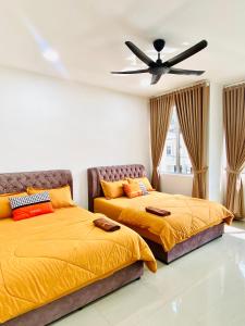 2 Betten in einem Schlafzimmer mit Deckenventilator in der Unterkunft LH Homestay Suite Gua Musang- Masjid Mekah in Gua Musang
