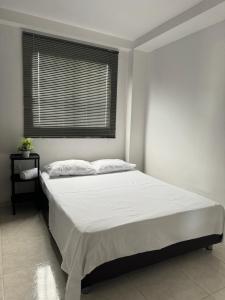 een witte slaapkamer met een bed en een raam bij Apartamento amoblado para familia y amigos in San Vicente de Chucurí