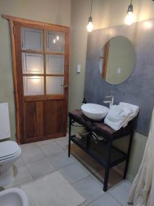 uma casa de banho com um lavatório, um espelho e um WC. em La Genoveva Posada entre Viñedos em Villa Unión
