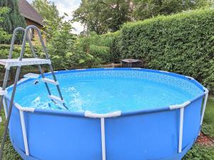 una silla sentada en una piscina azul con una silla en ella en Urlaubsmagie - Wohnung mit Grill, Terrasse & Pool -W5, en Lichtenhain