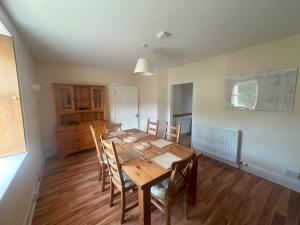 3 Bed Cottage in the Peaceful Village Wanlockhead في Wanlockhead: غرفة طعام مع طاولة وكراسي خشبية
