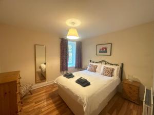 a bedroom with a bed with white sheets and a mirror at 3 Bed Cottage in the Peaceful Village Wanlockhead in Wanlockhead