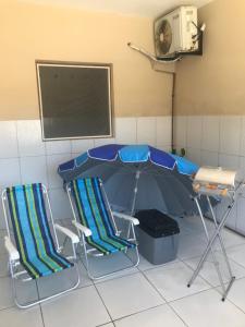 2 Stühle, ein Tisch und ein Regenschirm in einem Zimmer in der Unterkunft Casa Praia São José Maragogi 50m Mar in São José da Coroa Grande