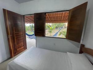 een slaapkamer met een bed en een open raam bij Sítio Paraíso do Caju in Barreirinhas