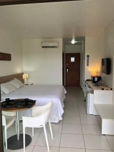 a hotel room with a bed and a table and a kitchen at Iloa Flat Barra São Miguel-Alagoas in Barra de São Miguel