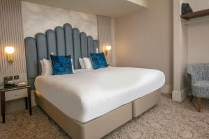 a large bed with blue pillows in a hotel room at Best Western Clifton Hotel in Folkestone